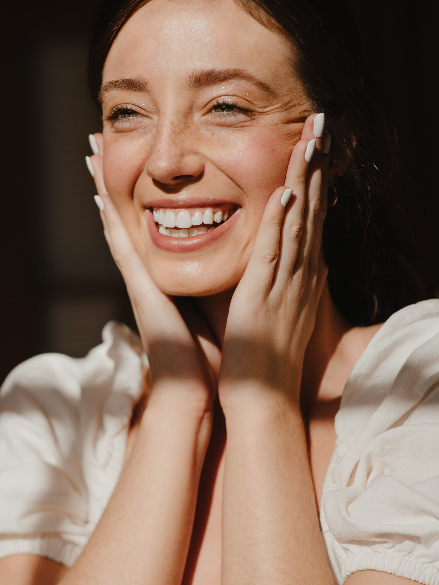 Smiling woman holding her face in bright sunlight